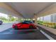 Undercover parking area showcasing a red sports car with building architecture and surrounding greenery at 7907 Sailboat Key S Blvd # 108, South Pasadena, FL 33707