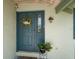 Welcoming front door with decorative wreath and sconce, complemented by potted plants at 909 Silver Palm Way, Apollo Beach, FL 33572