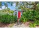 Backyard shed surrounded by lush greenery featuring a red door at 1042 S Sterling Ave, Tampa, FL 33629