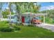 Charming home with a bright red door, lush green lawn, a covered carport, and tropical landscaping at 1042 S Sterling Ave, Tampa, FL 33629