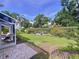 Spacious backyard featuring a well-manicured lawn, privacy hedges, and a screened-in patio with brick pavers at 1358 Forestedge Blvd, Oldsmar, FL 34677