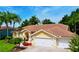 Charming yellow home featuring a tile roof, three-car garage, and lush tropical landscaping with mature palm trees at 1358 Forestedge Blvd, Oldsmar, FL 34677