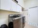 Modern laundry room with front-load washer and dryer, overhead cabinets, sink, and tile flooring at 1358 Forestedge Blvd, Oldsmar, FL 34677