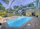 Sparkling in-ground pool with a screened enclosure, surrounded by a brick patio and lush landscaping at 1358 Forestedge Blvd, Oldsmar, FL 34677