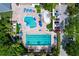 Aerial view of community pools with sun umbrellas and palm trees, including a splash pad at 1358 Forestedge Blvd, Oldsmar, FL 34677
