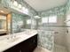 Bathroom with double vanity, shower, and decorative wallpaper at 16413 Rivers Reach Blvd, Parrish, FL 34219