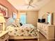 Well-lit bedroom with decorative coral art, white furnishings, and tropical themed bedding at 16413 Rivers Reach Blvd, Parrish, FL 34219