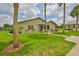 Charming home exterior features a large, well-maintained lawn with mature palm trees and landscaping at 1905 Canterbury Ln # 17, Sun City Center, FL 33573