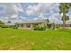 Charming home exterior features a large, well-maintained lawn and mature palm trees, with red shutters on the windows at 1905 Canterbury Ln # 17, Sun City Center, FL 33573