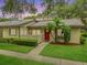 Charming single-story home with vibrant landscaping and a welcoming red front door at 200 Gretchen Ct, Oldsmar, FL 34677