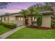 Front exterior home view featuring tropical trees, landscaping, and charming curb appeal at 200 Gretchen Ct, Oldsmar, FL 34677