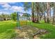 A backyard swing set is surrounded by green grass and mature trees at 210 Lake Hobbs Rd, Lutz, FL 33548