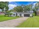 Single story home boasts a well-maintained lawn, stone facade, and a long driveway at 210 Lake Hobbs Rd, Lutz, FL 33548