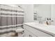 Bright bathroom with a single sink vanity, a large mirror and a shower with a gray and white curtain at 34196 Polacca Ln, Wesley Chapel, FL 33543
