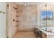 Elegant bathroom featuring a tiled shower, glass door, built-in shelves, and a soaking tub near a bright window at 4012 W Obispo St, Tampa, FL 33629