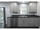 Well-lit kitchen with gray cabinets, stainless steel dishwasher, and double sink under a window at 5018 Pine St, Seffner, FL 33584