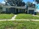 Charming single-story home featuring a brick facade, lush front lawn, and an attached single car garage at 641 Geneva Pl, Tampa, FL 33606