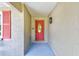 Covered entryway featuring a vibrant red front door and textured walls at 8402 Roxboro Dr, Hudson, FL 34667