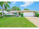 Charming single-story home featuring a lush green lawn, vibrant landscaping, and a bright red front door at 8402 Roxboro Dr, Hudson, FL 34667