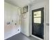 Well-lit utility room featuring a tankless water heater and convenient access to outside with a black door at 8402 Roxboro Dr, Hudson, FL 34667
