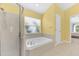 Bright bathroom features a soaking tub under a window, a separate shower, and tile flooring at 10813 Rockledge View Dr., Riverview, FL 33579