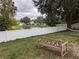 View of backyard with a bench, hammock, and a white vinyl fence near the pond at 12216 Southbridge Ter, Hudson, FL 34669