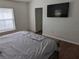 Bedroom featuring a mounted TV, light-colored walls, wood-look floors, and a glimpse of the walk-in closet at 12216 Southbridge Ter, Hudson, FL 34669