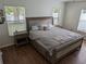 Bedroom with wood floors, neutral-toned furniture, windows with blinds, and a king bed with upholstered headboard at 12216 Southbridge Ter, Hudson, FL 34669