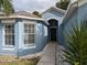 Inviting front entry with a walkway leading to the front door and large windows at 12216 Southbridge Ter, Hudson, FL 34669