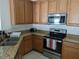 Functional kitchen with stainless steel appliances, granite countertops, and wooden cabinets at 12216 Southbridge Ter, Hudson, FL 34669