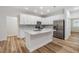 Modern kitchen features white cabinets, stainless steel appliances, a center island, and wood-look flooring at 12910 Prestwick Dr, Riverview, FL 33579