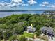 Stunning aerial view of the home nestled among trees with a lake in the background and lush landscaping at 1600 Lonesome Pine Ln, Tarpon Springs, FL 34689
