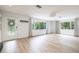 Bright living room with light wood floors, neutral walls, large windows, and a decorative glass front door at 1600 Lonesome Pine Ln, Tarpon Springs, FL 34689