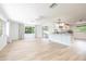 Bright, spacious living room with light wood floors, white walls, and open access to kitchen counter with bar stools at 1600 Lonesome Pine Ln, Tarpon Springs, FL 34689