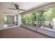 Spacious sunroom featuring a ceiling fan, screens, and outdoor views of the trees and backyard at 1600 Lonesome Pine Ln, Tarpon Springs, FL 34689