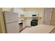 Well-lit kitchen with white cabinetry, appliances, and laminate countertops at 16501 Harper Pond Ln # 308, Odessa, FL 33556