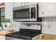 Close up of GE microwave and stove in white-cabinet kitchen, with window at 17207 Bosley Dr, Spring Hill, FL 34610