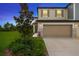 Two-story home boasting a two-car garage, stone accents, and lush landscaping under a twilight sky at 17741 Tawny Malt Pl, Land O Lakes, FL 34638