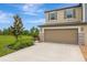 Daytime view of a two-story home showcasing a two-car garage, stone accents, and landscaped front yard at 17741 Tawny Malt Pl, Land O Lakes, FL 34638