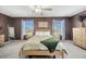 Comfortable main bedroom featuring a ceiling fan, neutral carpet, and large windows with neighborhood views at 17741 Tawny Malt Pl, Land O Lakes, FL 34638
