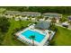Aerial view of a community pool with lounge chairs surrounded by green spaces and neighborhood townhomes at 17741 Tawny Malt Pl, Land O Lakes, FL 34638