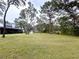Expansive backyard with mature trees, a green lawn, brick pizza oven and a house with a covered porch at 17926 Calkins Ct, Spring Hill, FL 34610