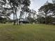 Expansive backyard with mature trees, green lawn, and a glimpse of the house with a covered porch at 17926 Calkins Ct, Spring Hill, FL 34610