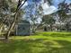 View of backyard featuring a shed with rustic decor, mature trees, and a sprawling green lawn at 17926 Calkins Ct, Spring Hill, FL 34610