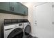 Laundry room with gray cabinets and modern washer and dryer with overhead storage at 1803 E Powhatan Ave, Tampa, FL 33610