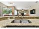 Open-concept kitchen featuring granite countertops, a stainless steel sink, and a breakfast bar overlooking the living area at 2009 Raven Manor Dr, Dover, FL 33527