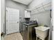 Laundry room with modern washer and dryer, utility sink, storage and tile floor at 2009 Raven Manor Dr, Dover, FL 33527