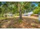 Expansive backyard featuring mature trees and the rear exterior of the charming single-story home with a screen porch at 208 Palmetto W Rd, Nokomis, FL 34275