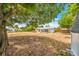 Expansive backyard featuring mature trees and the rear exterior of the charming single-story home with a screen porch at 208 Palmetto W Rd, Nokomis, FL 34275
