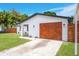 Charming single-story home with a wooden garage door, manicured lawn, and white exterior at 208 Palmetto W Rd, Nokomis, FL 34275